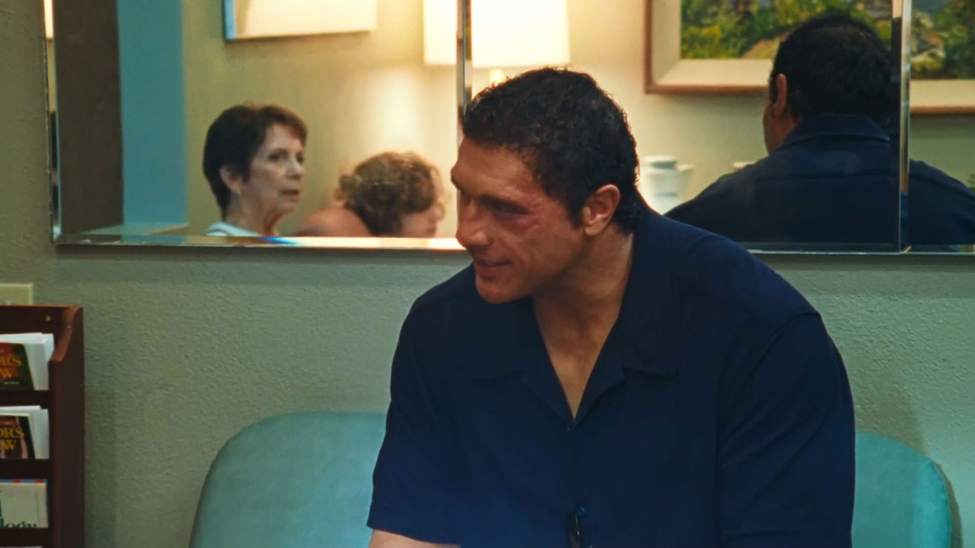 دواین جانسون راک نشسته روی صندلی با زنی که در آینه پشت سرش پیداست حرف میزند در نمایی از فیلم ماشین کوبنده به کارگردانی بنی سفدی