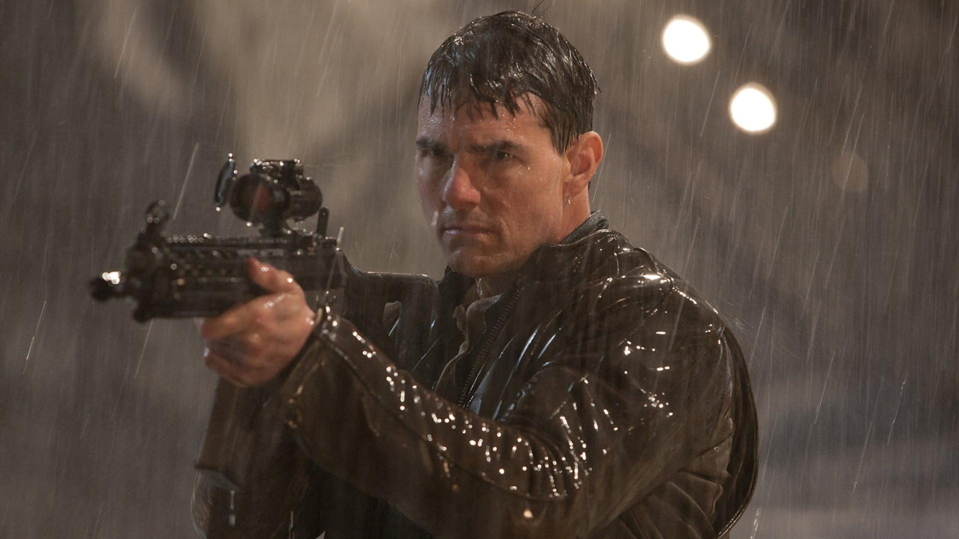تام کروز (Tom Cruise) در حالی که در باران با تفنگ نشانه می‌رود