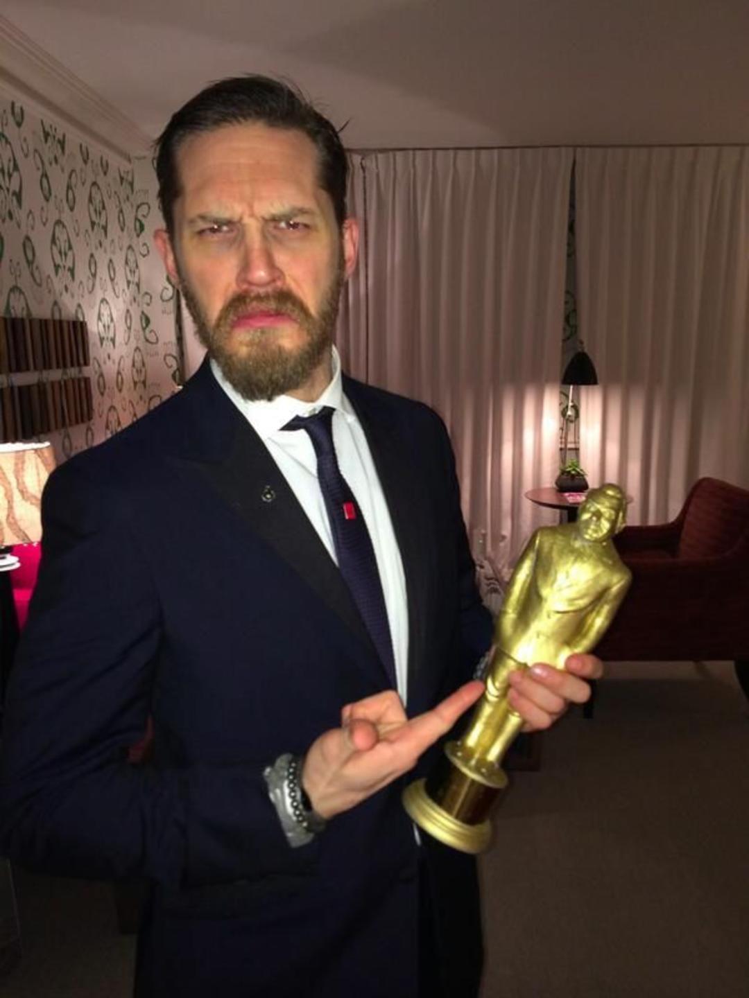تام هاردی (Tom Hardy) در حال نگه داشتن یک تندیس طلایی جایزه