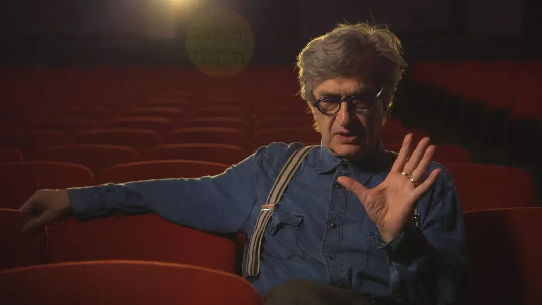 ویم وندرس (Wim Wenders) در میان صندلی‌های قرمز یک سالن سینما