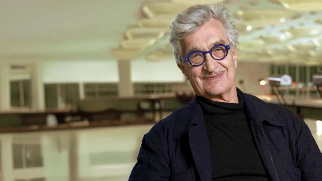ویم وندرس (Wim Wenders) با عینک آبی در محیطی با نور ملایم
